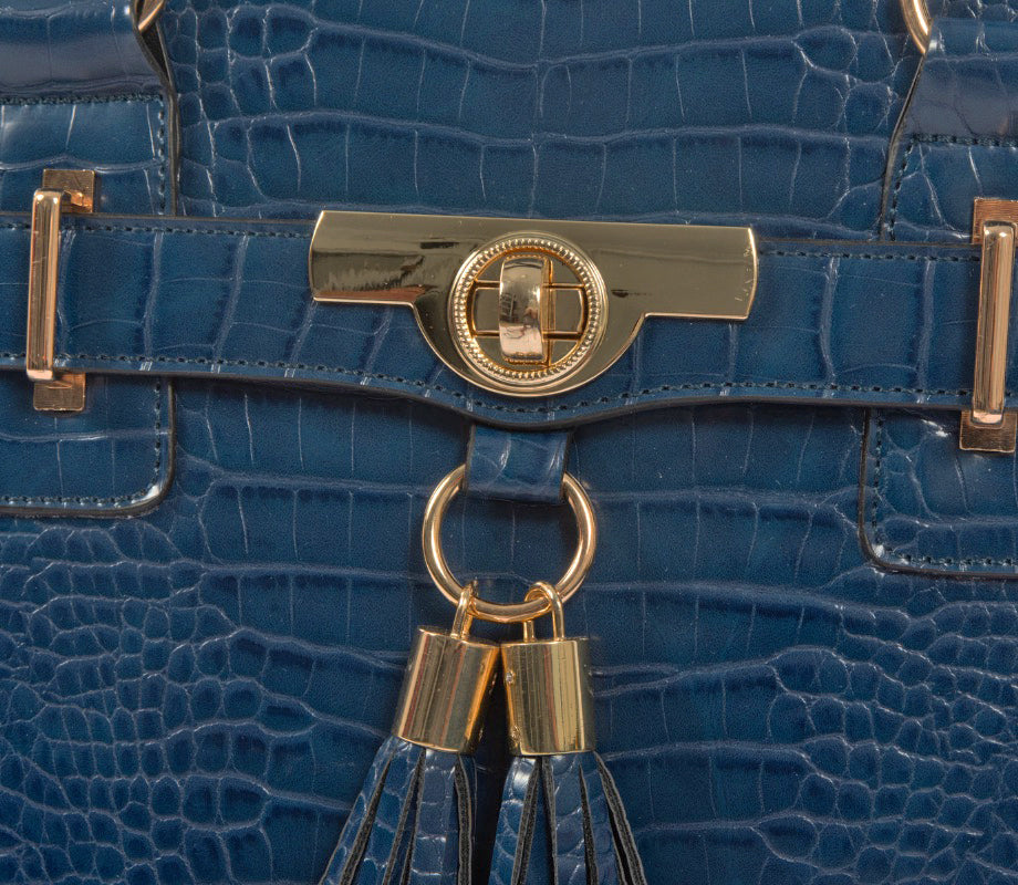 Close-up of a deep blue alligator leather rolling briefcase, showcasing the intricate texture, gold metal twist pendant, and precision stitching. The high-quality craftsmanship highlights the attention to detail in the bag’s construction and design. Designed for detail conscious professionals, this elegant rolling tote combines fashion and organization in a compact sleek frame. Great for chic women who want a distinctive, office-appropriate statement piece that doubles as a rolling business bag.
