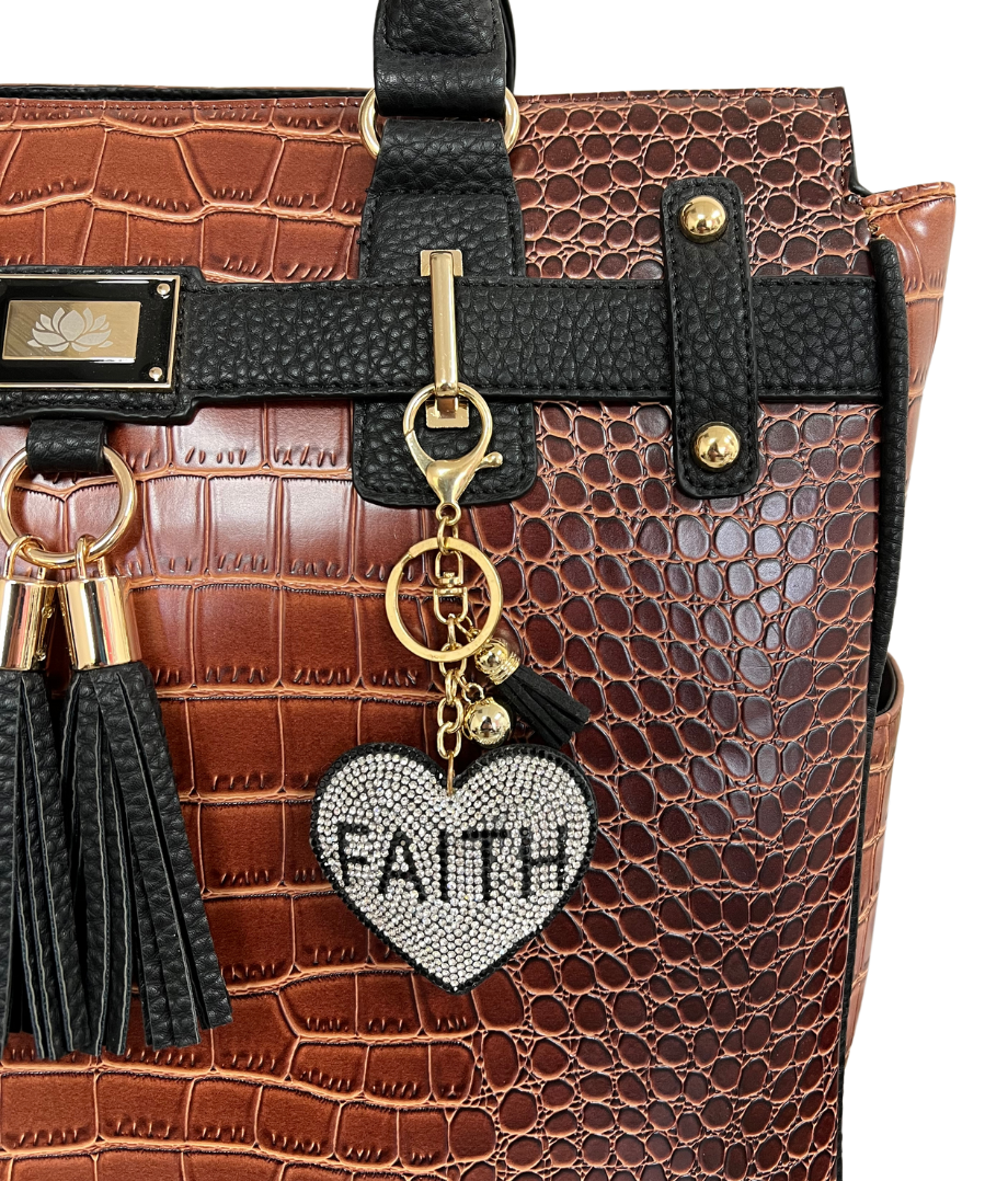 Connected with a bag charm chain, this keychain charm, this heart bag charm is shown on a brown vegan leather rolling laptop bag. Ideal for women of faith, this bag decor is ideal for blessed gifts, church gifts, and gifts of spirit.