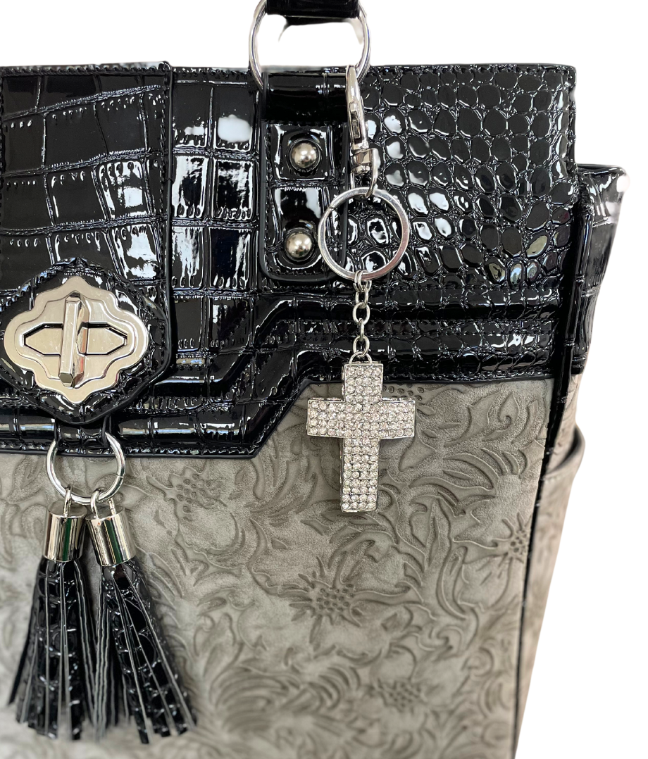 The sparkle silver cross keychain and bag pendant for women shown on a grey and black vegan leather briefcase for ladies. This accessory shows off your unique style on your bible bag and church bag for ladies. Put this bling bag charm on your work bag or travel bag and make a statement!