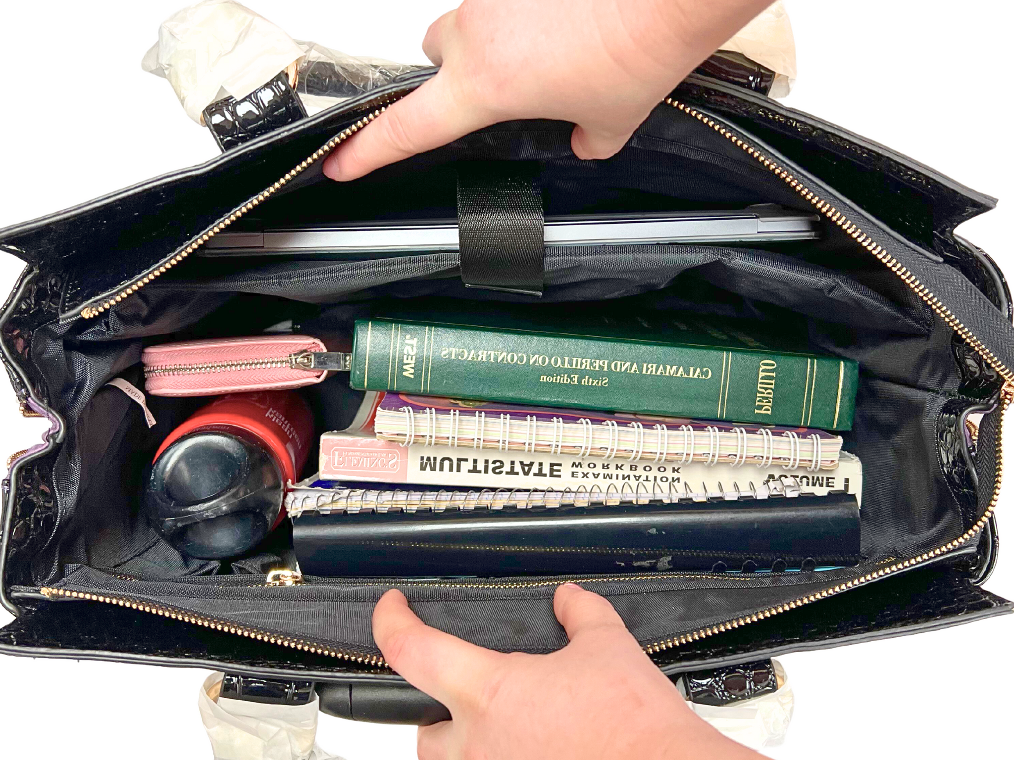 Black fabric interior of the purple laptop bag with wheels filled with work essentials  such as a wallet, water bottle, notebooks, workbooks, textbooks, laptop, chargers, cords, phone, and keys. This bag can also fit travel essentials such as a passport, boarding pass, travel clothes, toiletry bags, makeup bag, documents, shoes, umbrella, and headphones.