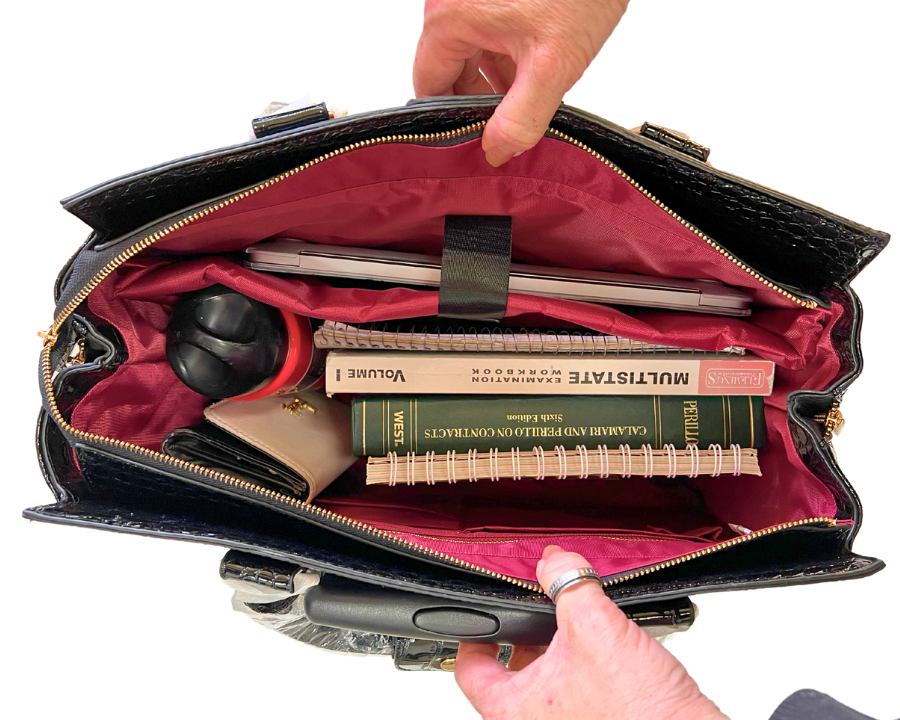 Interior of a faux leather laptop bag for women, filled with work and travel essentials, including a laptop, notebooks, wallet, and other necessities. Ideal for professionals on the go, offering organization and style in one spacious bag.