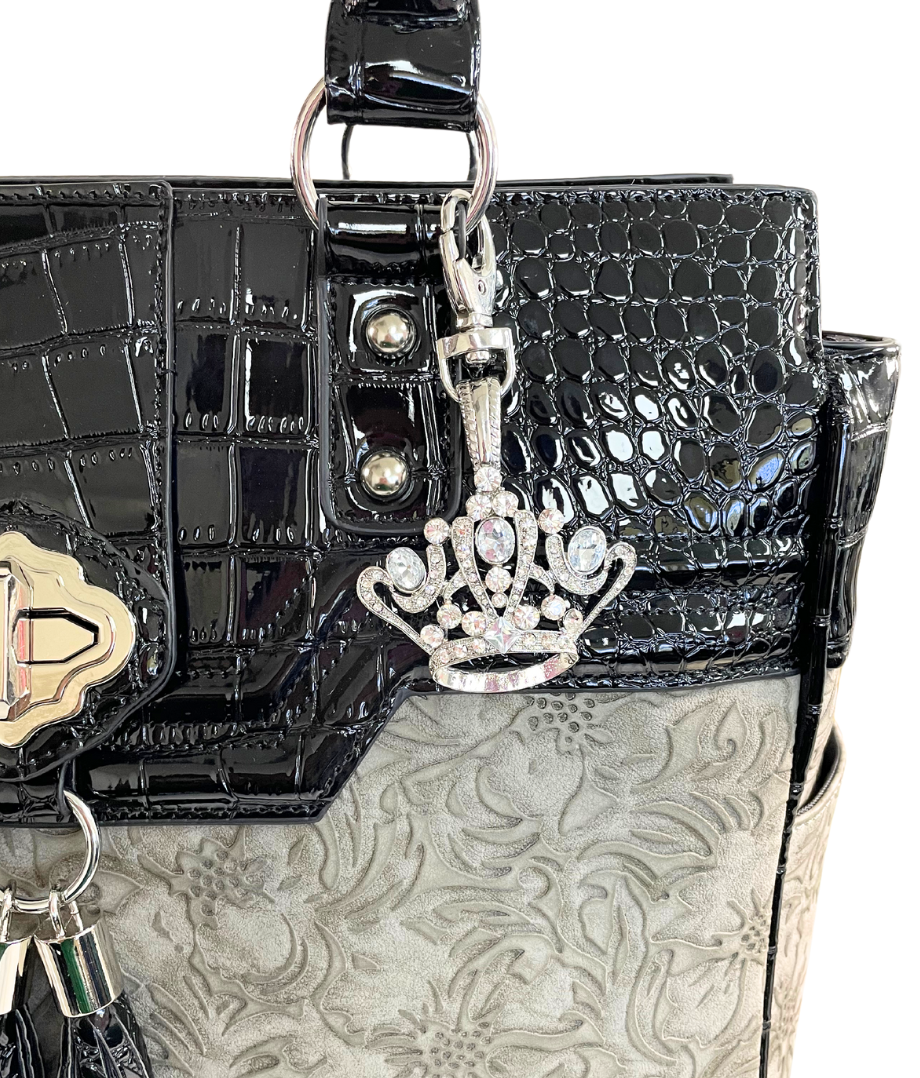 The silver bling crown charm on the grey and black floral tote bag for women with wheels. This charm is the perfect accessory for bags to show off her unique coquette style and to accent her princess style fit for a queen.