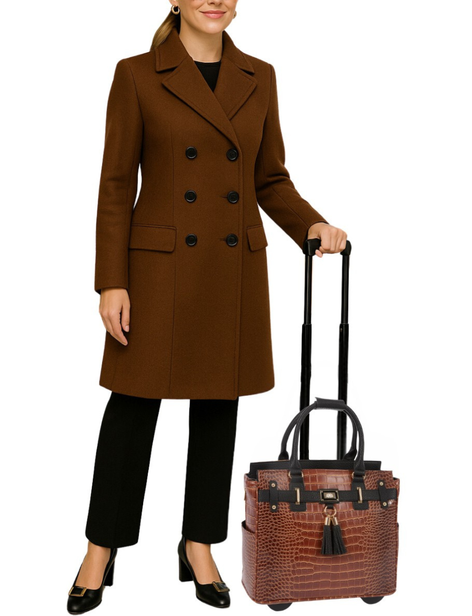 A business woman stands with her briefcase on wheels that she uses as her office rolling bag to store her office essentials for women such as notebooks for work, nurse accessories for work, business card holder, and chic small business essentials. This  bag elevates her outfit while offering space for her laptop, documents, tablet, and personal items. Designed for ambitious women who want to feel empowered by their accessories, this rolling purse is perfect for leaders, creatives, and educators.
