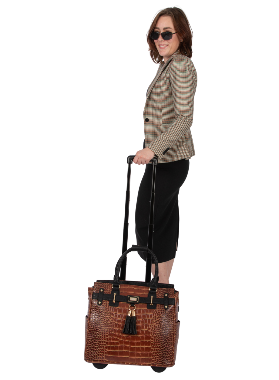 A business woman stands with her briefcase on wheels that she uses as her office rolling bag to store her office essentials for women such as notebooks for work, nurse accessories for work, business card holder, and chic small business essentials.