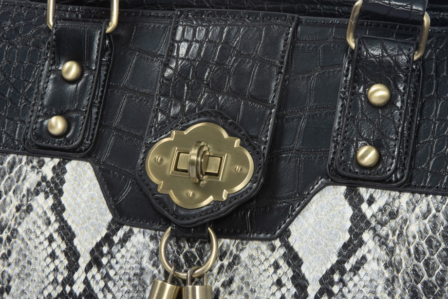 Close-up of a python print bag showcasing a brushed brass twist pendant, luxurious textured fabrics, and meticulous craftsmanship. Perfect blend of style and quality, ideal for professionals seeking a statement piece for work or travel.
