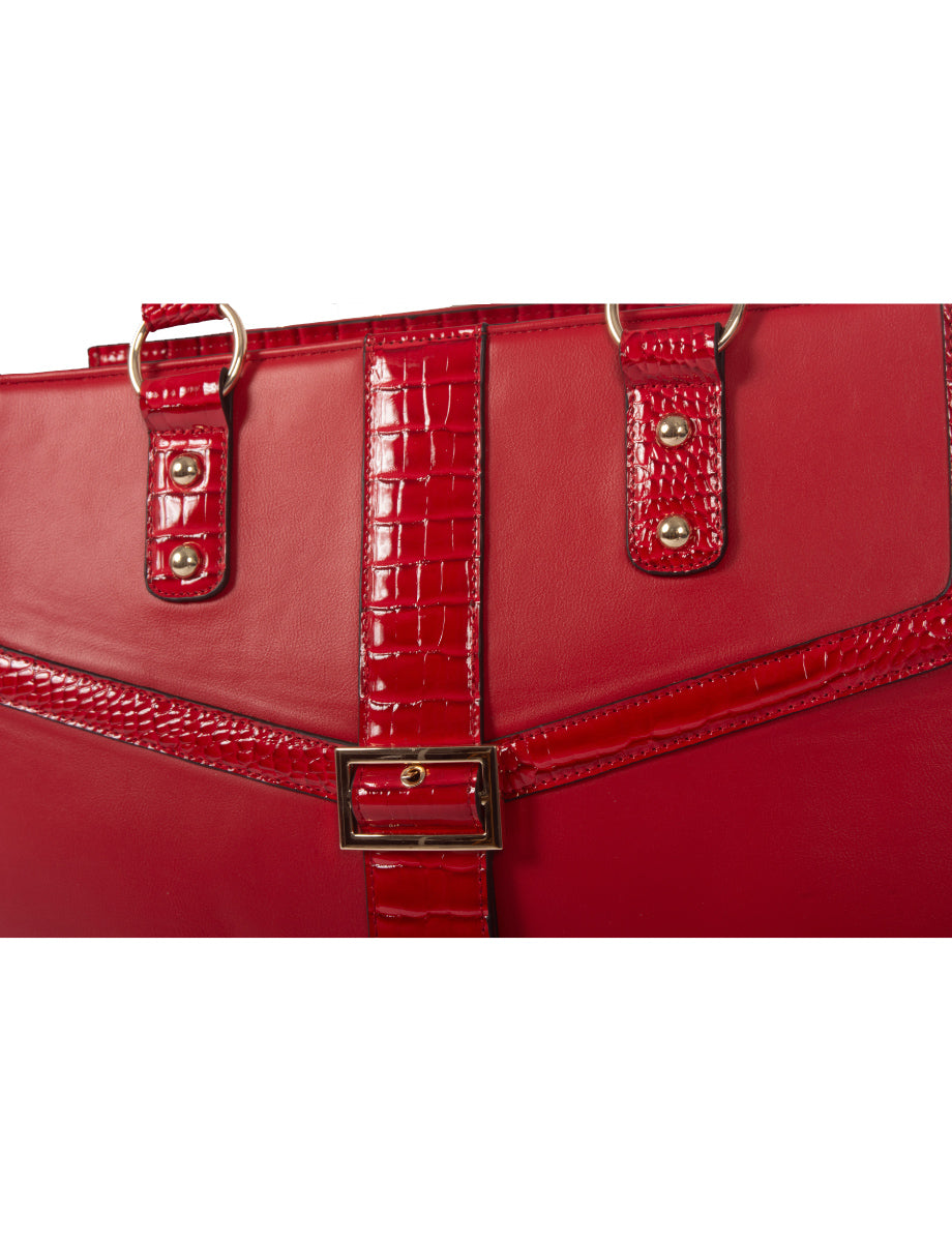 An up close image of the red womens work bag. This laptop bag for women showcases red patent faux leather alligator embossing detail over a matte scarlet fabric. There are gold studs, gold rings, and a gold belt buckle to provide a contrast to the red coloration. This vegan leather bag provides a fun and jazzy, yet professional style to match your personal style while you elevate your career. 