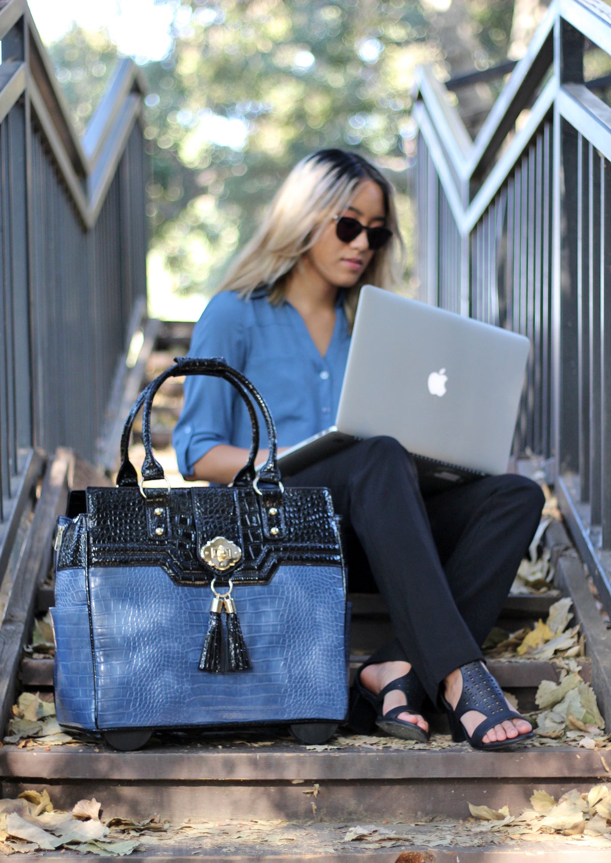 A woman in semi smart casual pinterest fashion office wear waits at a train station to commute to work. She holds her tote bag with laptop case that holds her office equipment supplies, staples office products, ada wallet, and bellabeat water bottle.