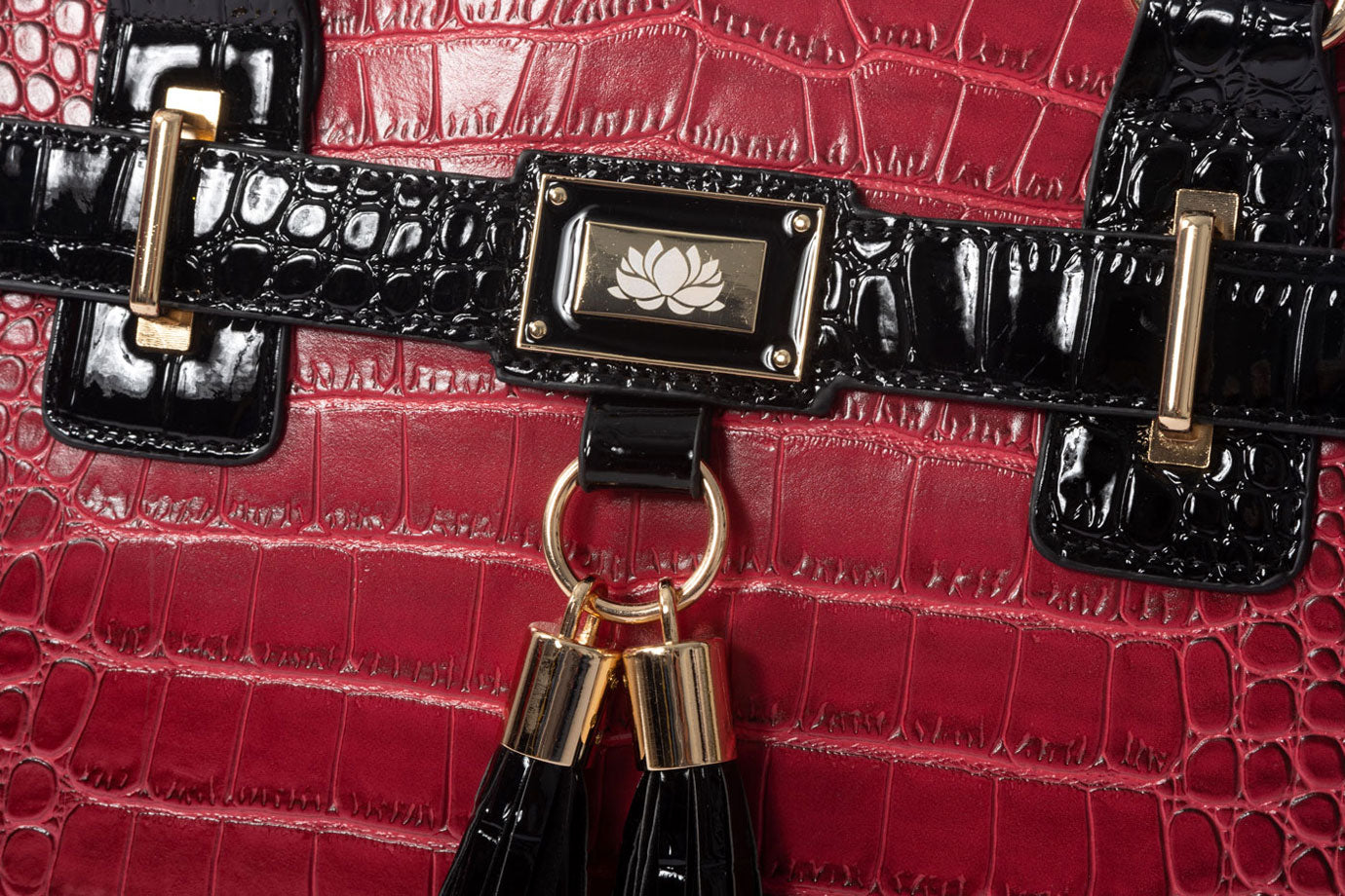 A zoomed image of the red and black purse with wheels and laptop compartment. The deep red is highlighted with gold and black tassels held with a gold ring, a gold lotus pendant, and other gold hardware. You will stand out with the shine on this bag! A luxurious bag for women that’s perfect for teachers, attorneys, or nurses. Use as a wheeled work tote to eliminate shoulder stress and keep all you need stylishly in tow. Makes a memorable gift for her for graduation, promotion, or just because.